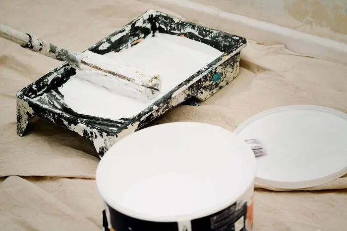 Rouleau et bac de peinture blanche sur un chantier de rénovation
