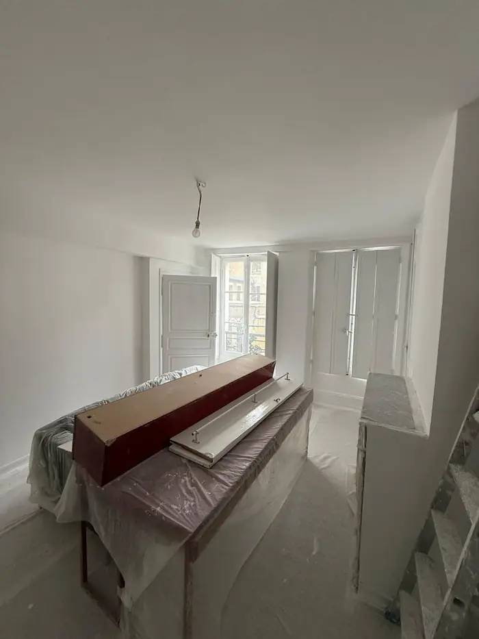 Chantier de peinture en cours, mobilier et sols protégés par des bâches
