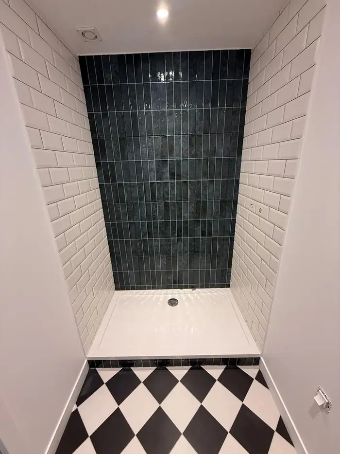 Salle de bain rénovée, faïence métro blanche et mur de douche bleu nuit