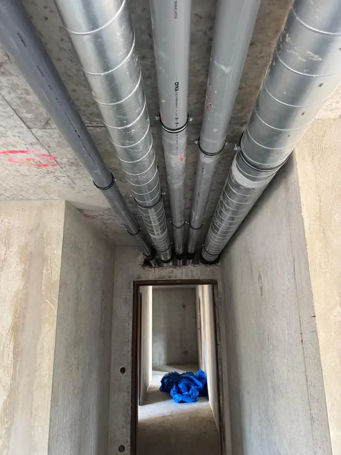 Cinq réseaux d'évacuation et de ventilation alignés au plafond d'un couloir d'immeuble neuf