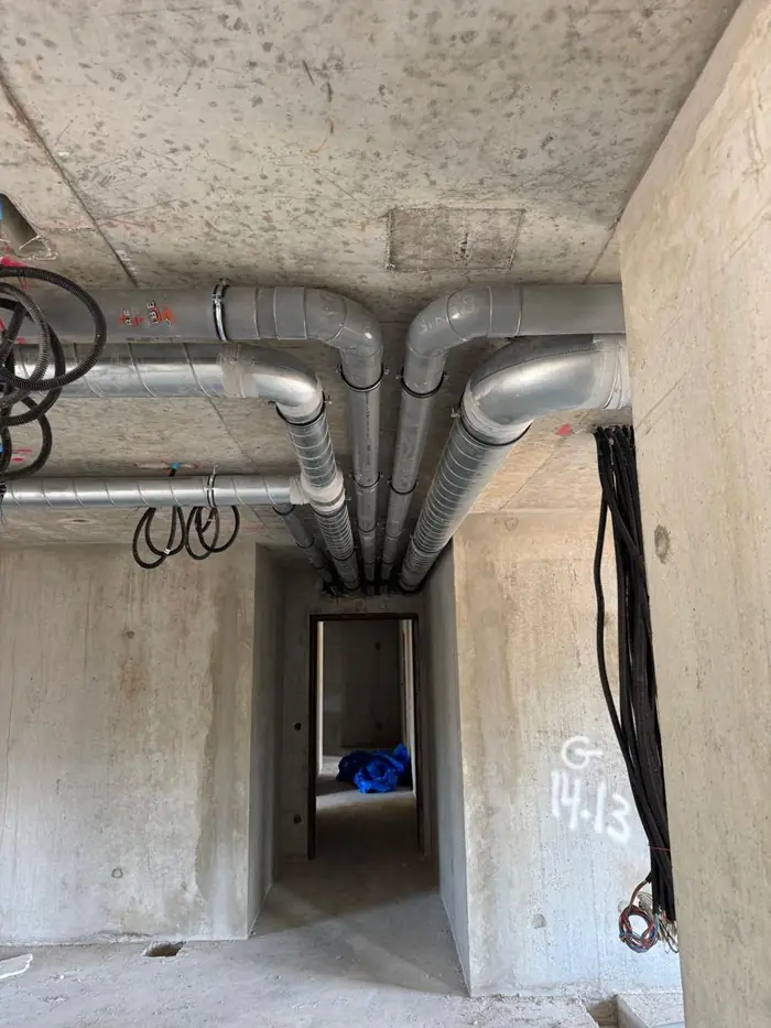 Coudes PVC et gaines galvanisées répartis vers les logements depuis le couloir