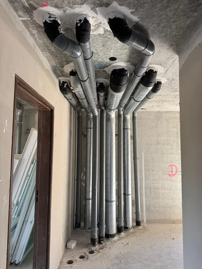 Descentes d'évacuation PVC et gaines de ventilation posées par gintáqua dans une gaine technique d'immeuble neuf