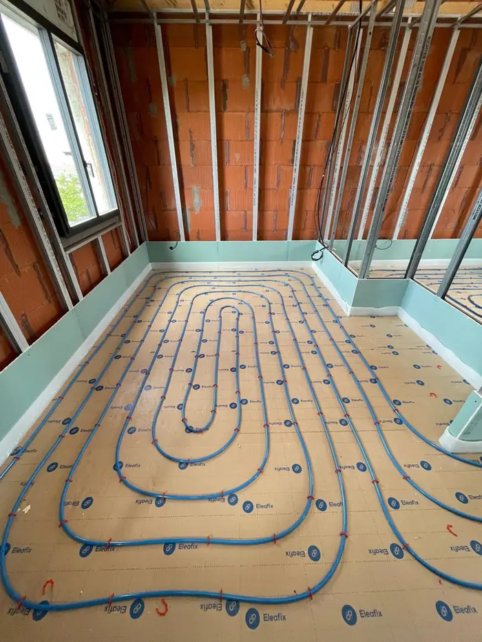 Plancher chauffant hydraulique en cours de pose, tubes fixés sur isolant