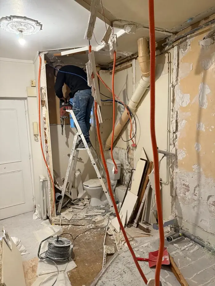 Artisan sur un escabeau pendant la démolition de la salle d'eau