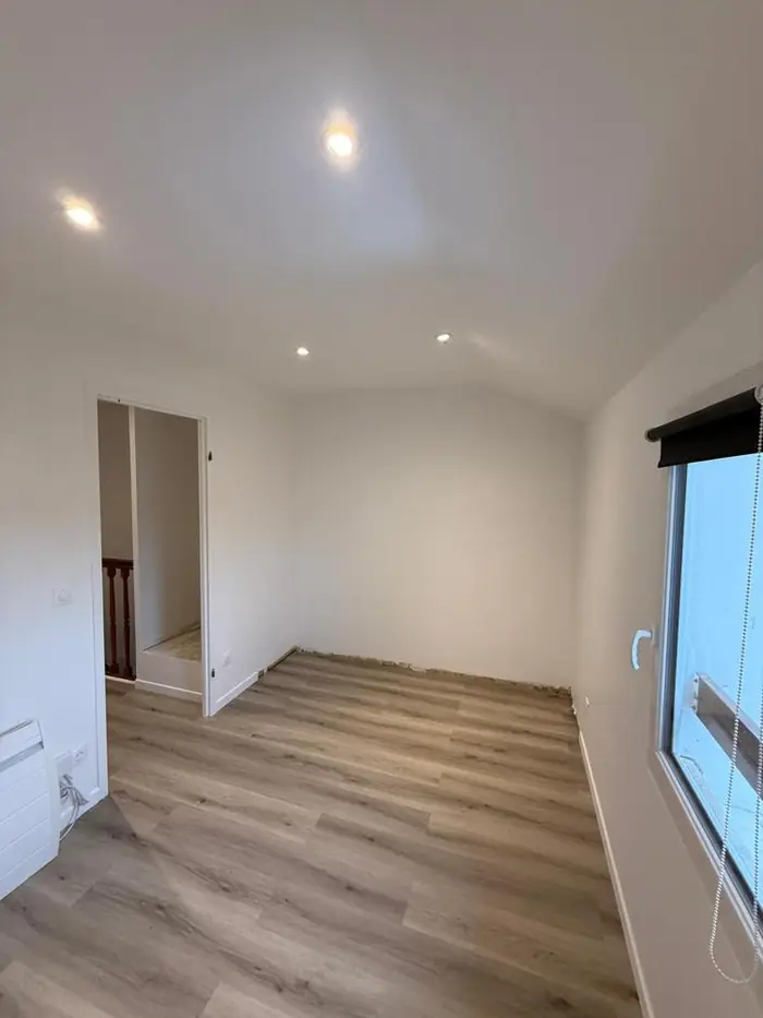 Chambre terminée avec spots, sol stratifié et ouverture vers le palier