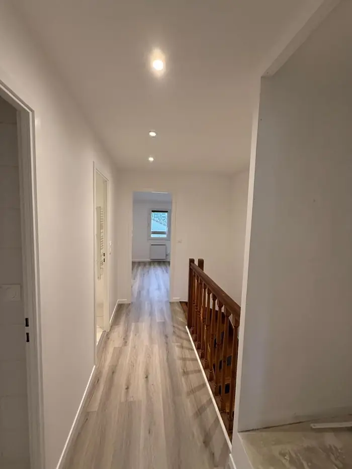 Couloir d'étage rénové avec sol stratifié continu jusqu'à la chambre