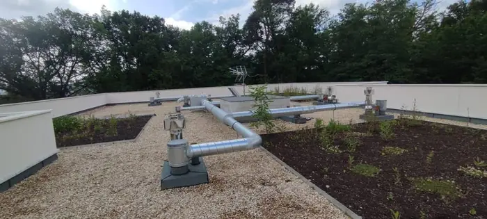 Gaines de ventilation et sorties de toiture réparties sur une terrasse gravillonnée