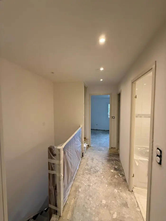 Palier d'étage en travaux, rampe protégée et sol brut