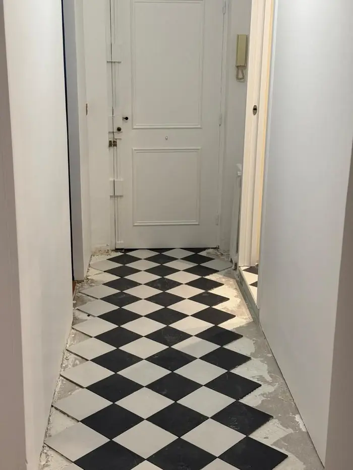 Pose d'un carrelage en damier noir et blanc dans le couloir d'entrée