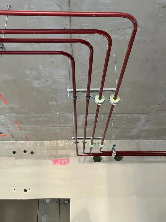 Réseau de chauffage en acier peint suspendu au plafond sur colliers isolés