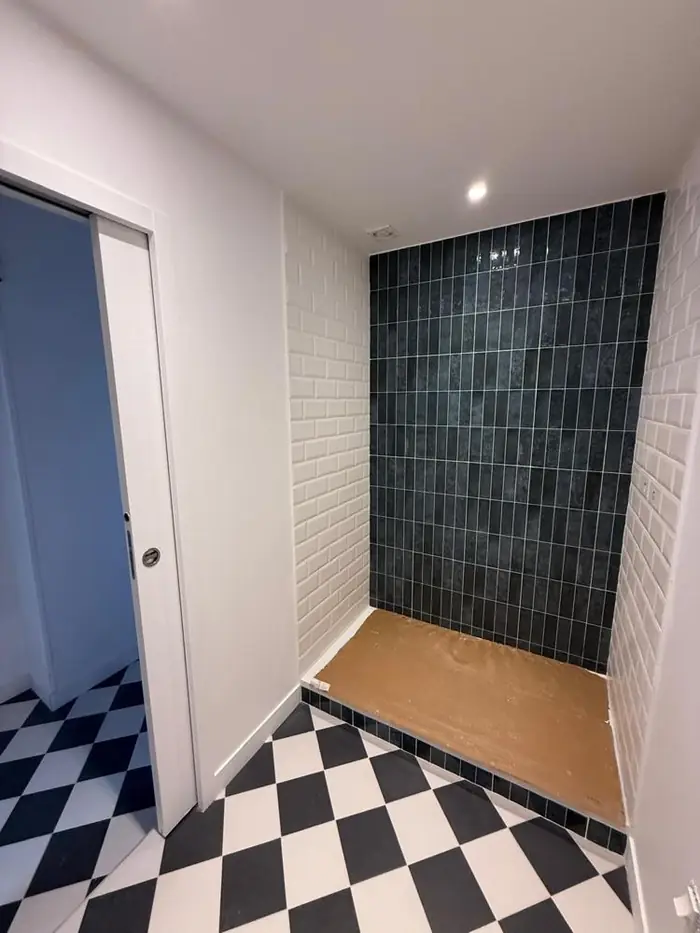 Salle d'eau terminée avec douche carrelée bleu nuit, carreaux métro blancs et sol en damier