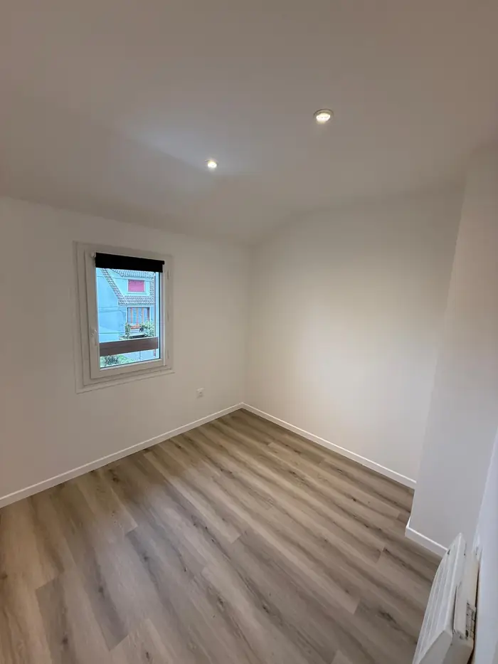 Chambre rénovée avec sol aspect chêne clair en pose droite, plinthes blanches assorties